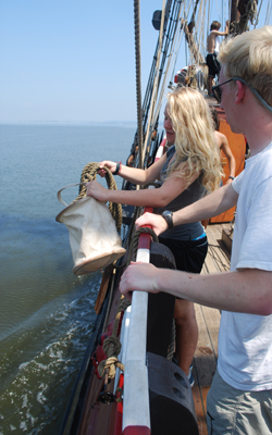 Hayley hurls a canvas bucket overboard to collect water.